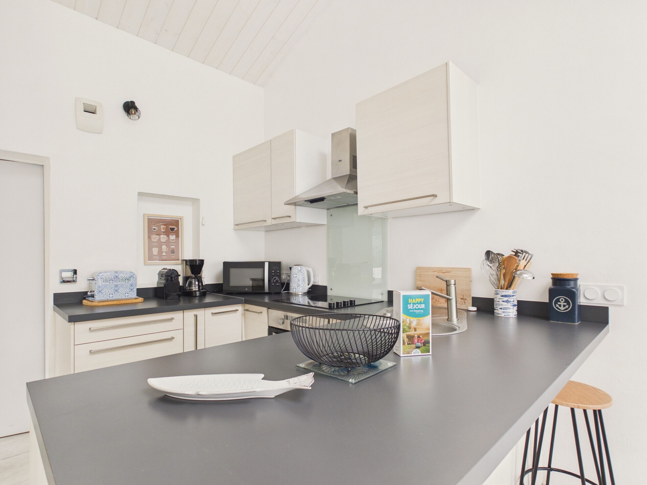 A modern kitchen with white cabinets, a black countertop, and a large island.