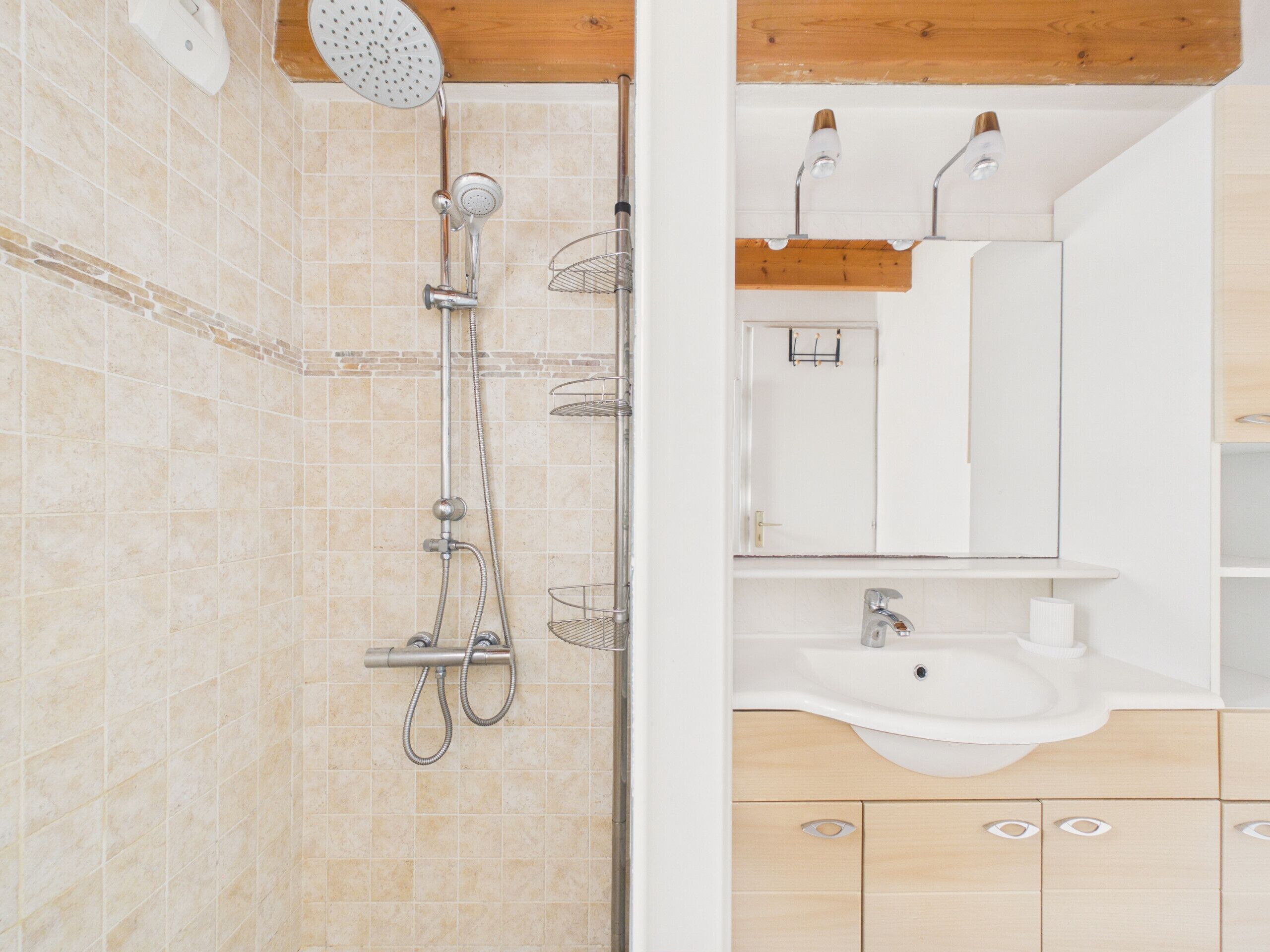A modern bathroom with a shower, sink, and wooden cabinets.