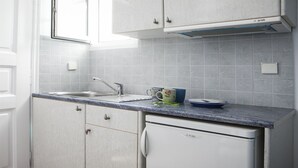 A kitchen with white cabinets, a sink, and a built-in dishwasher. - Asteri Hotel Ornos (Mykonos)