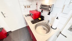 A modern kitchen with a stainless steel sink, a red toaster, and a built-in oven.