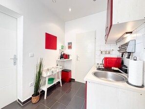 A modern kitchen with white cabinets, a red toaster, and a sink. - LIV:ON Studio King Bed & Kitchen - near Prater (Wien)