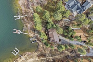 Ein Luftbild eines Küstengrundstücks mit Anlegesteg, Haus und umliegender Vegetation.
