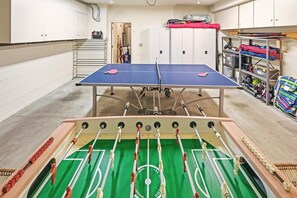 Ein Zimmer mit einer Tischfußballplatte, einem Pongtisch und Stauraumschränken.