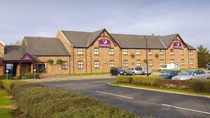 Ein Premier Inn Hotel mit Backsteinfassade, zahlreichen Fenstern und einem Parkplatz.
