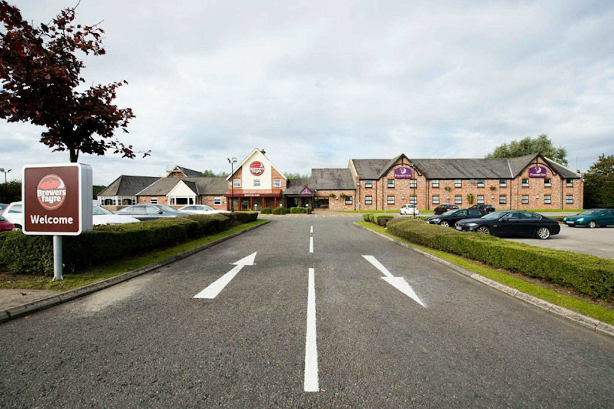 A road leading to a building with a 'Welcome' sign and a 'Brewers Fayre' sign.