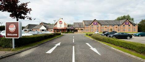 A road leading to a building with a 'Welcome' sign and a 'Brewers Fayre' sign.