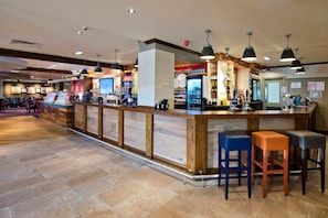 A bar area with a long counter, stools, and overhead lighting. - Premier Inn Wigan (Wigan)