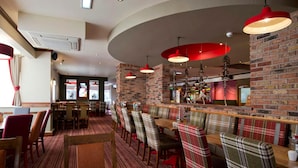 Ein Restaurant mit Backsteinwänden, karierten Sitzecken und roten Pendelleuchten.