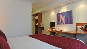 A hotel room with a bed, a desk, a chair, a coffee maker, and a painting on the wall. - Premier Inn Middlesbrough South Guisborough (Guisborough)