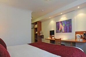 A hotel room with a bed, a desk, a chair, a coffee maker, and a painting on the wall. - Premier INN Middlesbrough South Guisborough (Guisborough)