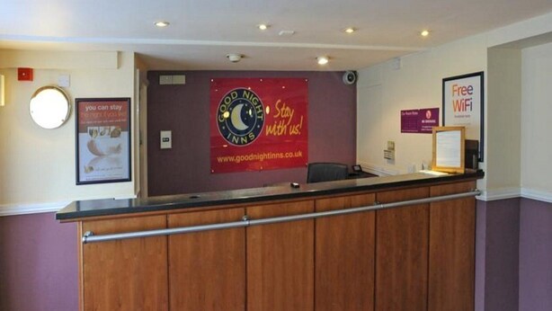 A reception area with a wooden counter, a 'Good Night Inns' sign, a 'Free WiFi' sign, and a 'You can stay' poster. - Premier Inn Middlesbrough South Guisborough (Guisborough)