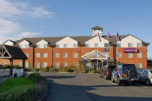 Un hotel con fachada de ladrillo, un acceso cubierto y varias banderas.