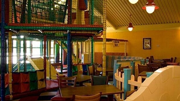 Un espace de jeux intérieur avec des structures d’escalade et des tables.