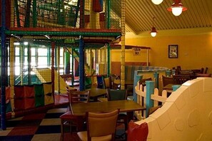 An indoor play area with climbing structures and tables.