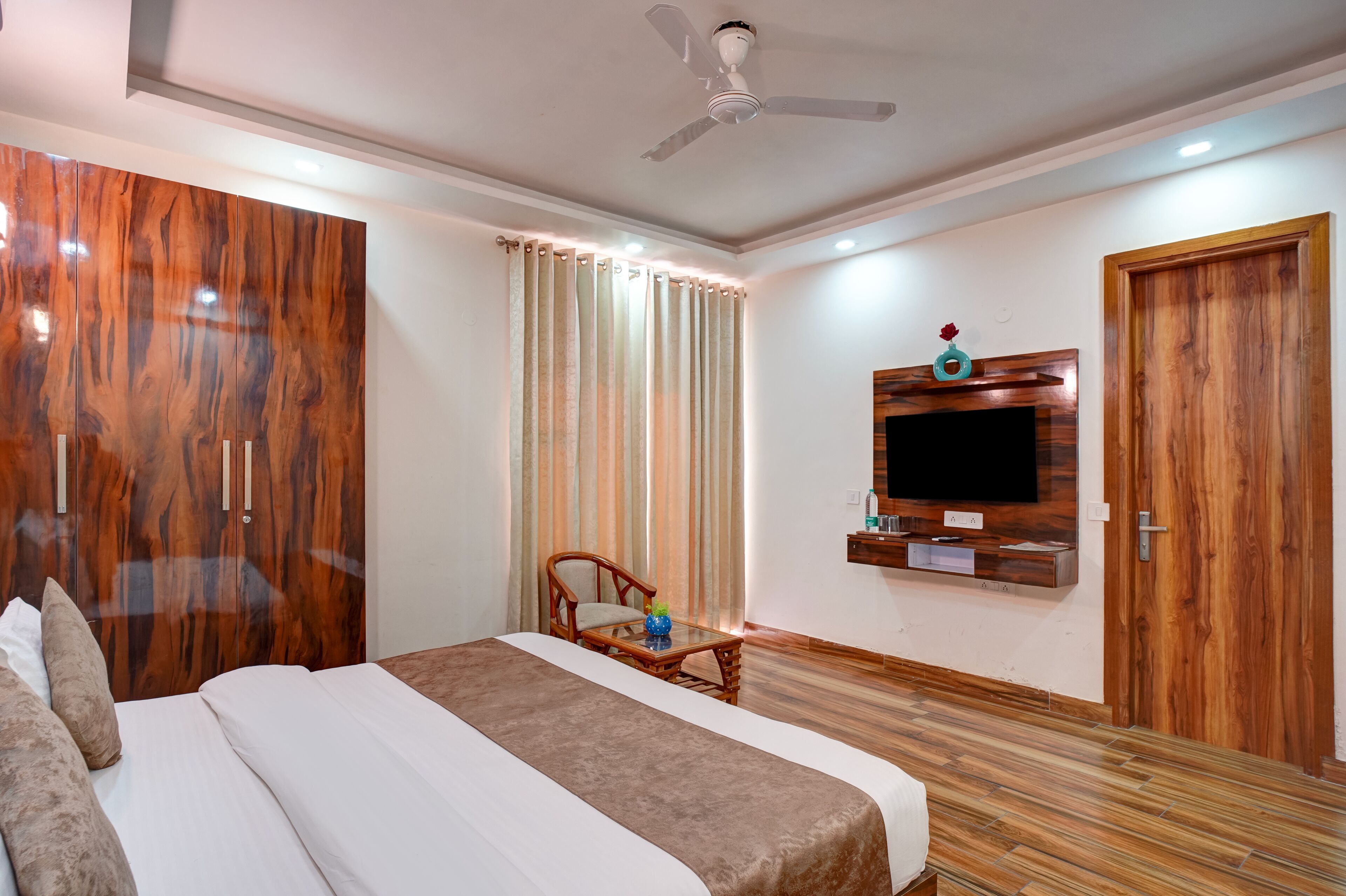 Une chambre d’hôtel équipée d’un lit, d’un bureau, d’une chaise, d’un téléviseur fixé au mur et d’un ventilateur de plafond.