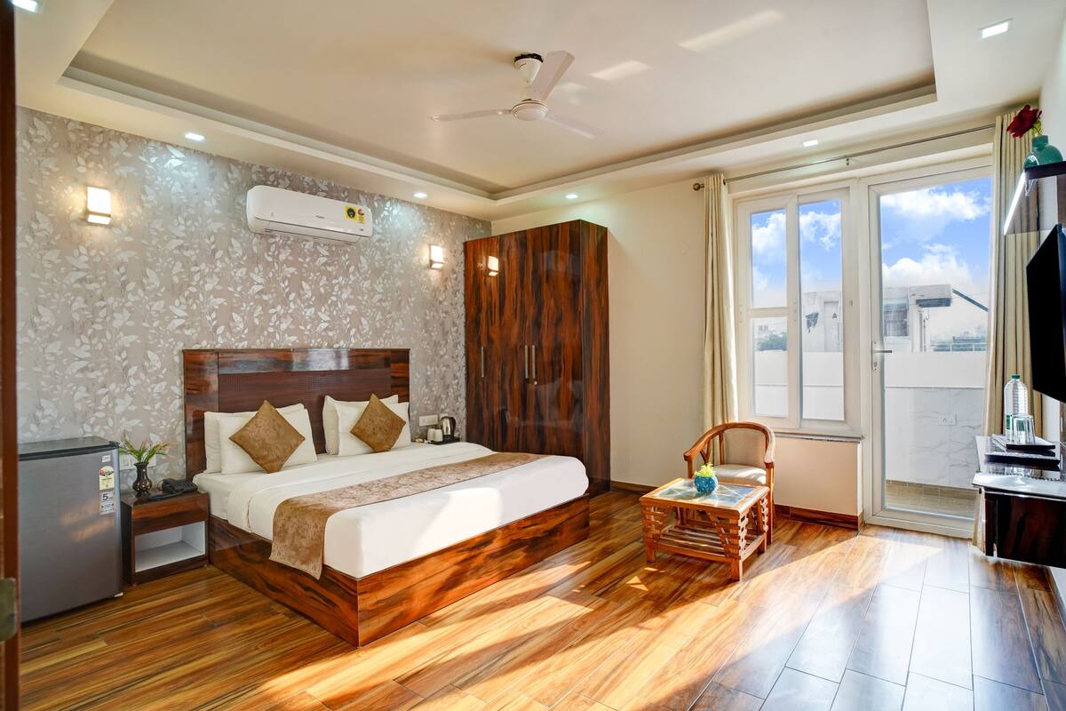 Habitación de hotel con cama de madera, armario, mesita y televisor.