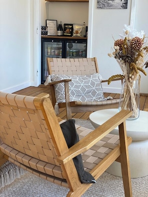 A room with a wooden bench, a patterned pillow, a vase with dried flowers, and a small table. - Klippen Hotel - Therns (Gudhjem)