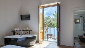 A modern bathroom with a bathtub, a toilet, a sink, and a TV mounted on the wall. - B&B Iancura (Santa Marina Salina)