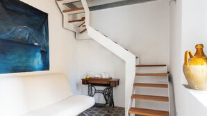 A staircase with wooden steps, a white wall, a sewing machine, and a painting. - B&B Iancura (Santa Marina Salina)