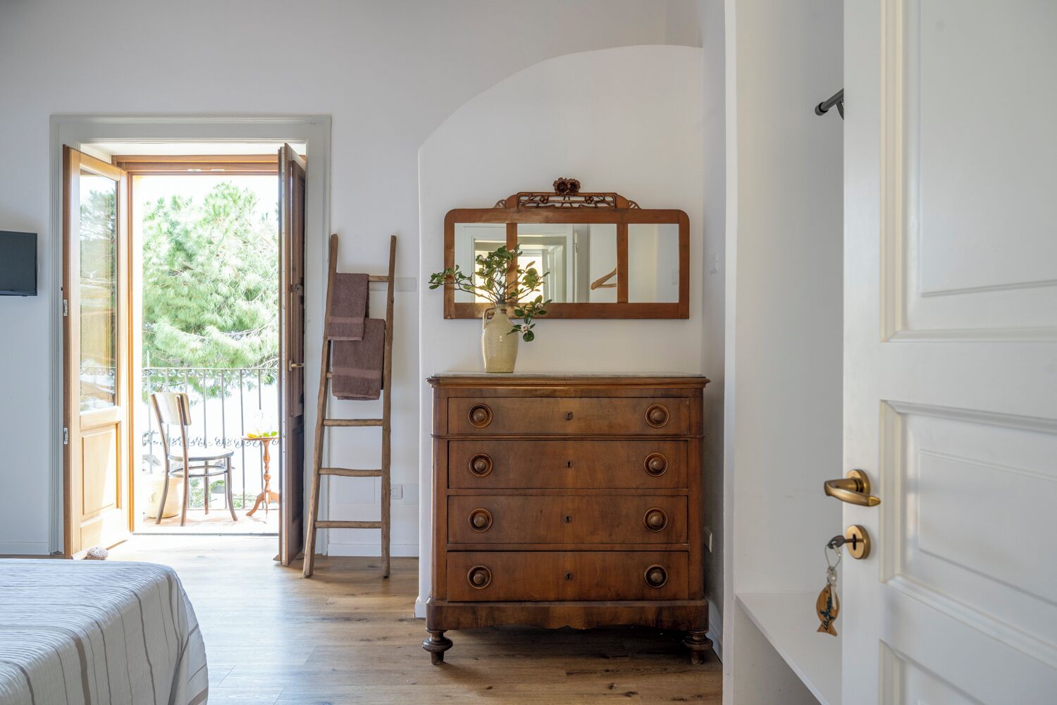 A room with a wooden dresser, a mirror, and a door.