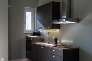 A modern kitchen with a built-in oven, a stainless steel range hood, and a window above the sink. - Eleganza Metropolitana (Turin)