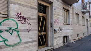 A building with a door, windows, and graffiti. - Eleganza Metropolitana (Turin)