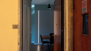 A hallway with a wooden door, a sign prohibiting smoking, and a dining area with a table and chairs. - Eleganza Metropolitana (Turin)