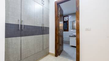 Una habitación con armario, puerta de madera y un vistazo a un baño con espejo y lavabo.