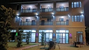 A multi-story building with balconies, large windows, and outdoor seating. - Mushrooms (Jinning)