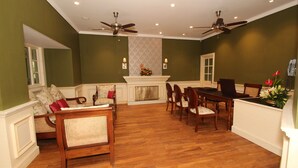 A dining area with a fireplace, wooden furniture, and ceiling fans. - Club Mahindra Mount Serene Munnar (Devikolam)