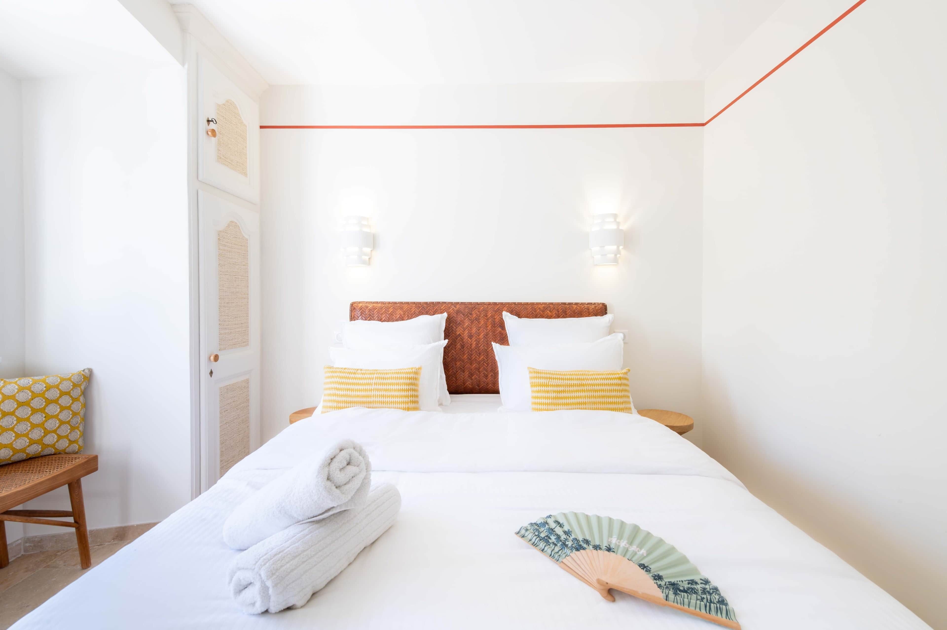 Une chambre d’hôtel comprenant un lit, deux tables de chevet, une chaise et un luminaire fixé au mur.