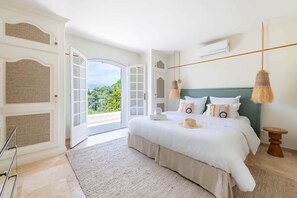 Ein Schlafzimmer mit einem großen Bett, Blick durch eine offene Tür und einer Hängelampe.