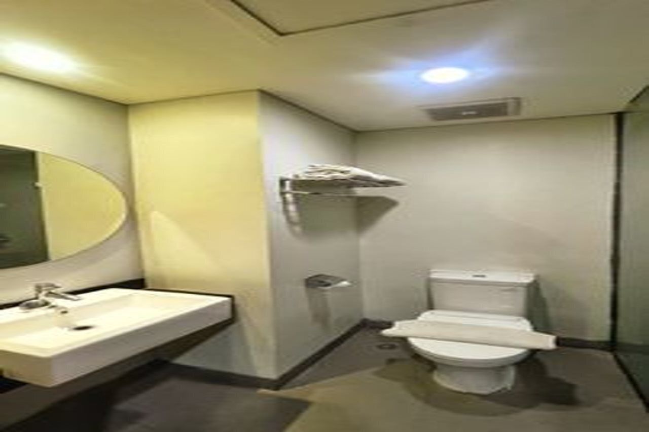 A small, compact bathroom with a white sink, mirror, and toilet.
