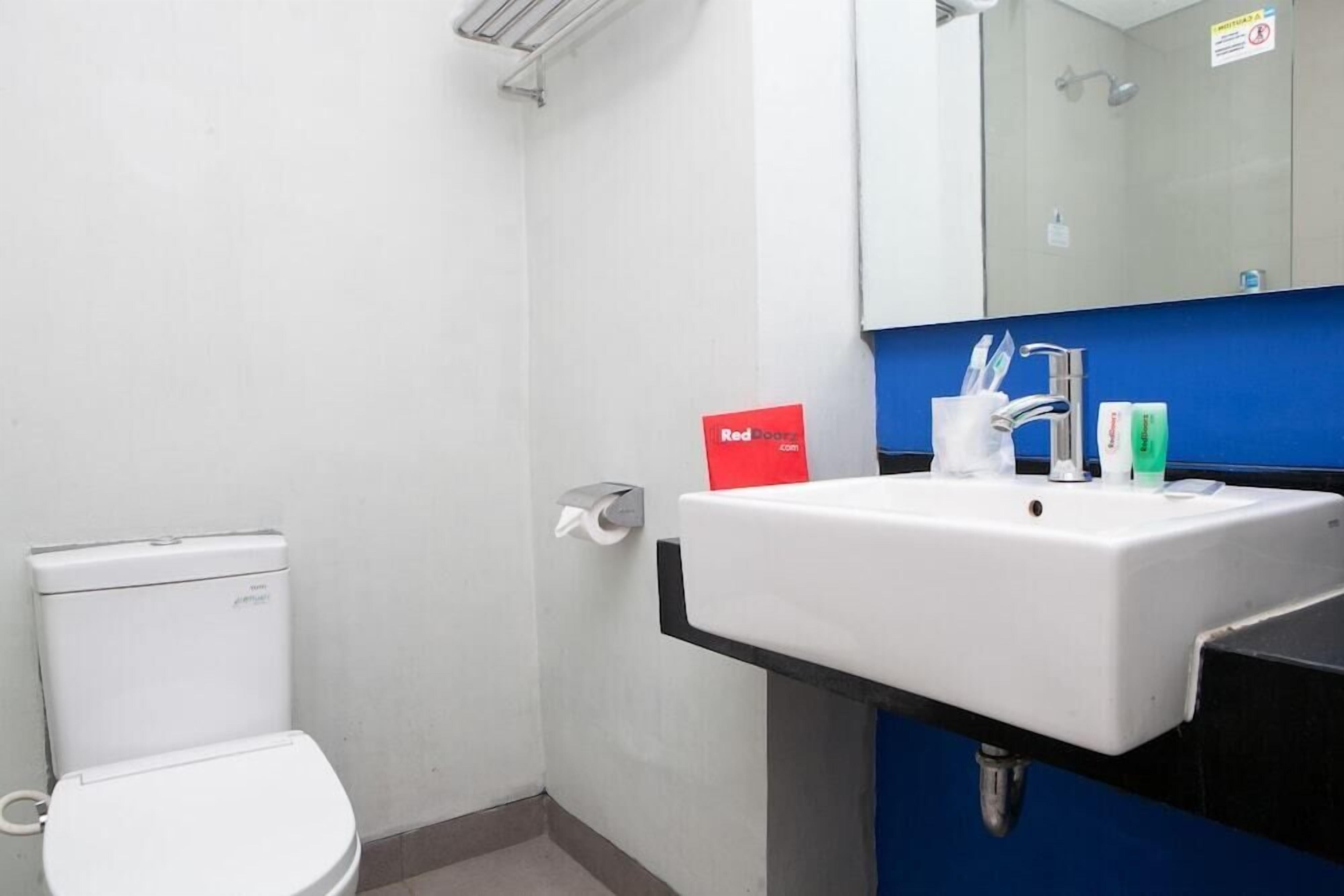 A bathroom with a white toilet, a sink with a blue countertop, and a mirror above the sink.