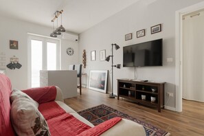 Una sala de estar con un sofá rojo, un televisor de pantalla plana, un aparador de madera y un tapete estampado.