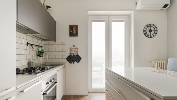 Eine moderne Küche mit weißen Schränken, einem Herd und einem großen Fenster.