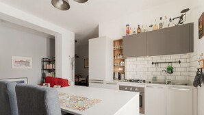 Eine moderne Küche mit weißen Schränken, einem Esstisch mit farbenfroher Tischmatte und einer sichtbaren Kücheninsel.