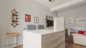 Ein modernes Wohnzimmer mit einem weißen Sofa, einem Glastisch und einem Fernseher auf einem Schrank.