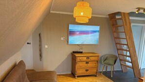 Een gezellige woonkamer met een bruine bank, een houten dressoir en een televisie aan de muur.