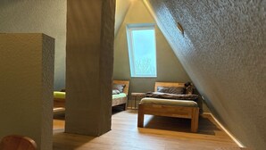 Een gezellig zolderkamer met schuine wanden, een houten bed, een klein tafeltje en een raam dat natuurlijk licht laat binnen.