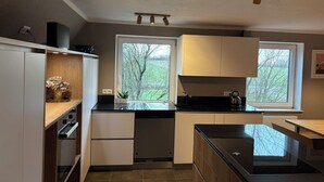 Een moderne keuken met witte kasten, een zwart aanrecht en een raam dat voor natuurlijk licht zorgt.