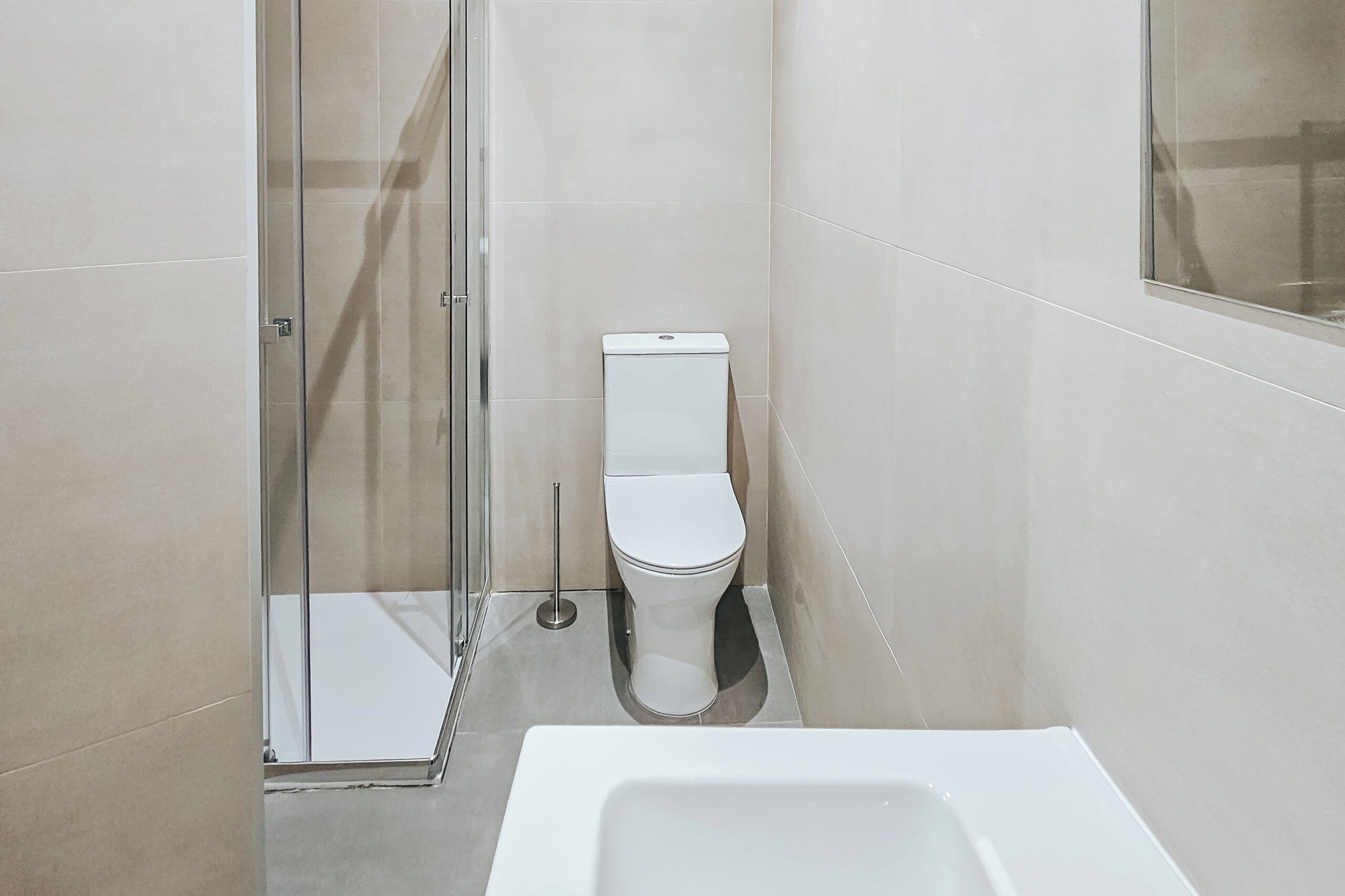 A modern bathroom with a glass shower enclosure, a white toilet, and a bathtub.