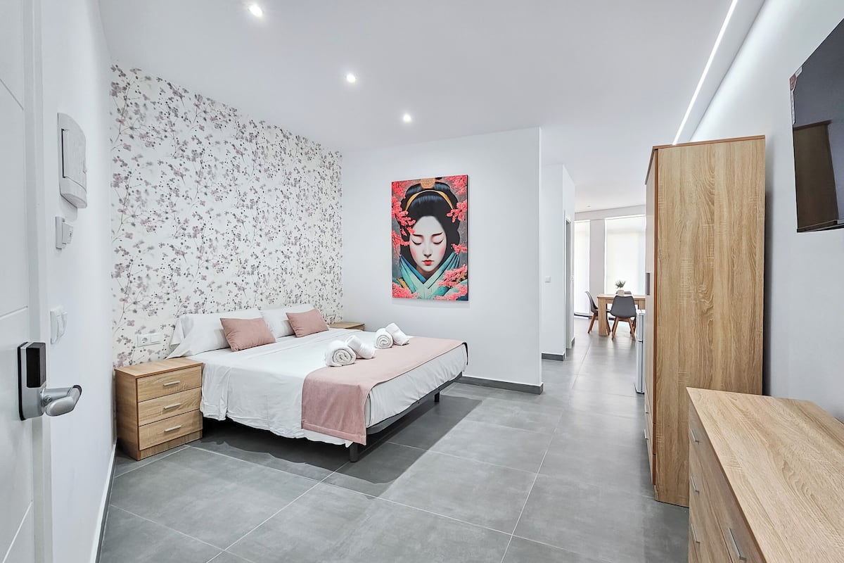 A modern bedroom with a bed, bedside tables, a wooden wardrobe, and a painting on the wall.