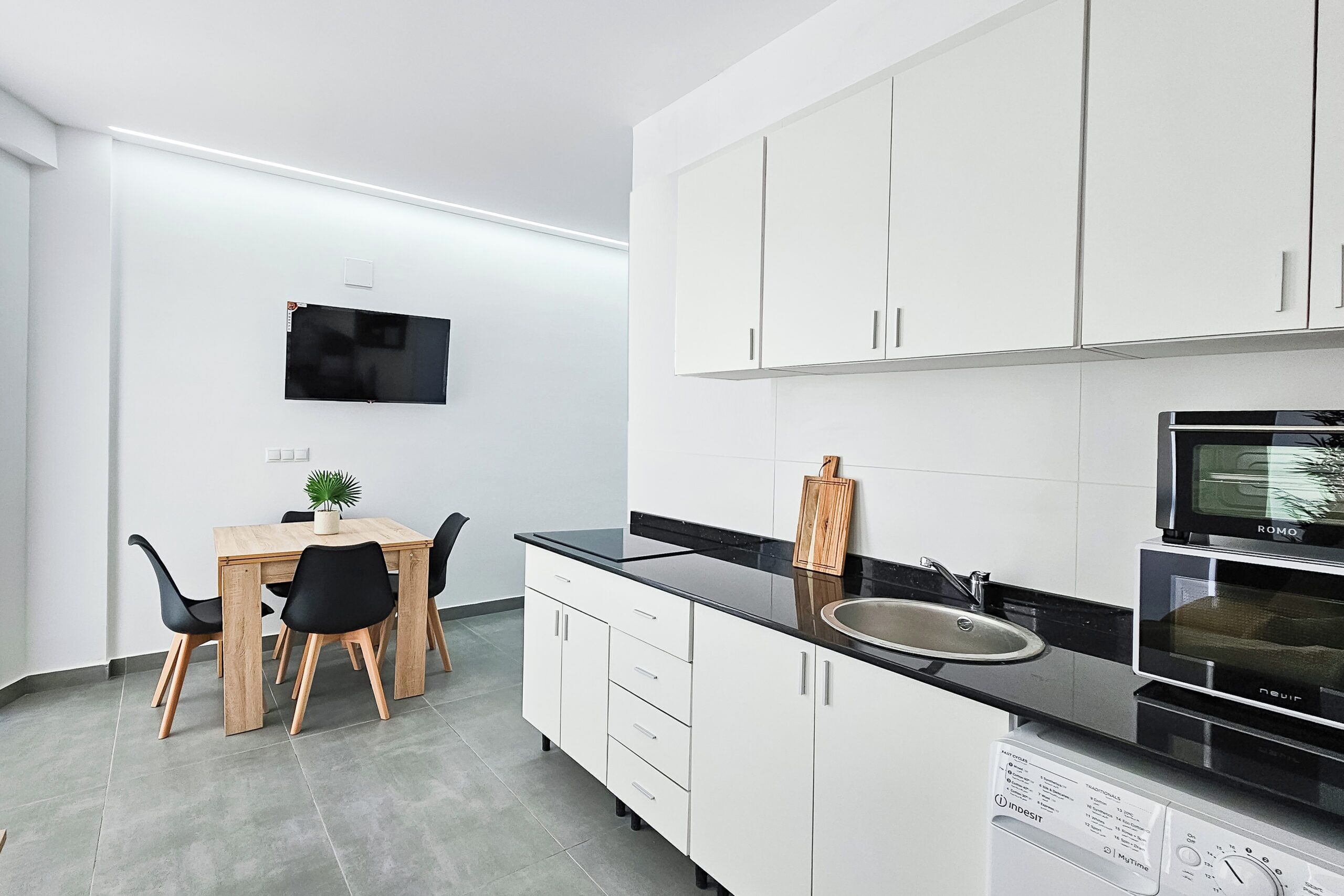 Eine moderne Küche mit weißen Schränken, einer schwarzen Arbeitsplatte und einem eingebauten Backofen.