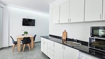 Eine moderne Küche mit weißen Schränken, einer schwarzen Arbeitsplatte und einem eingebauten Backofen.
