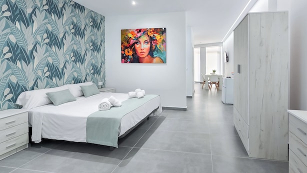 A modern bedroom with a large bed, a wardrobe, and a painting on the wall. - Ros Lil Suites (Alicante)