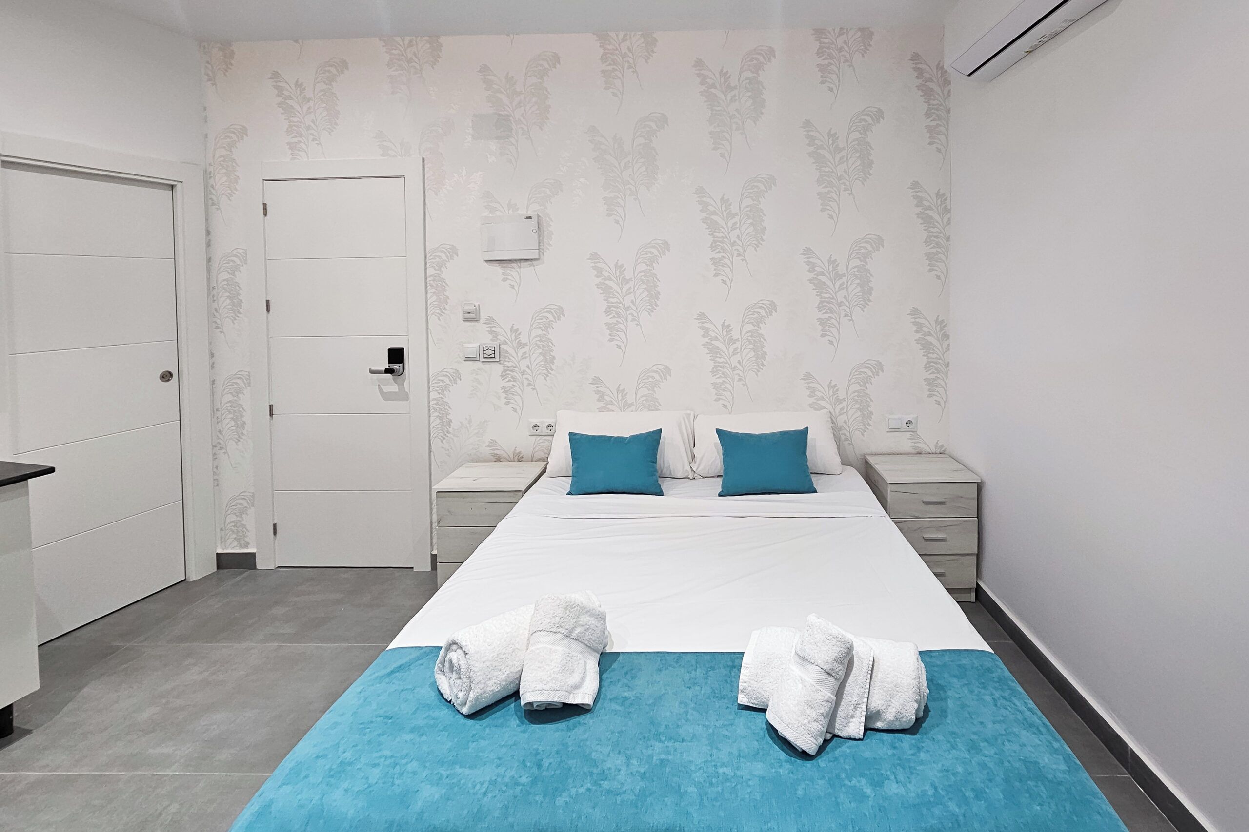 Ein Hotelzimmer mit einem Bett, zwei Nachttischen, einem Kleiderschrank und einer Badezimmertür.