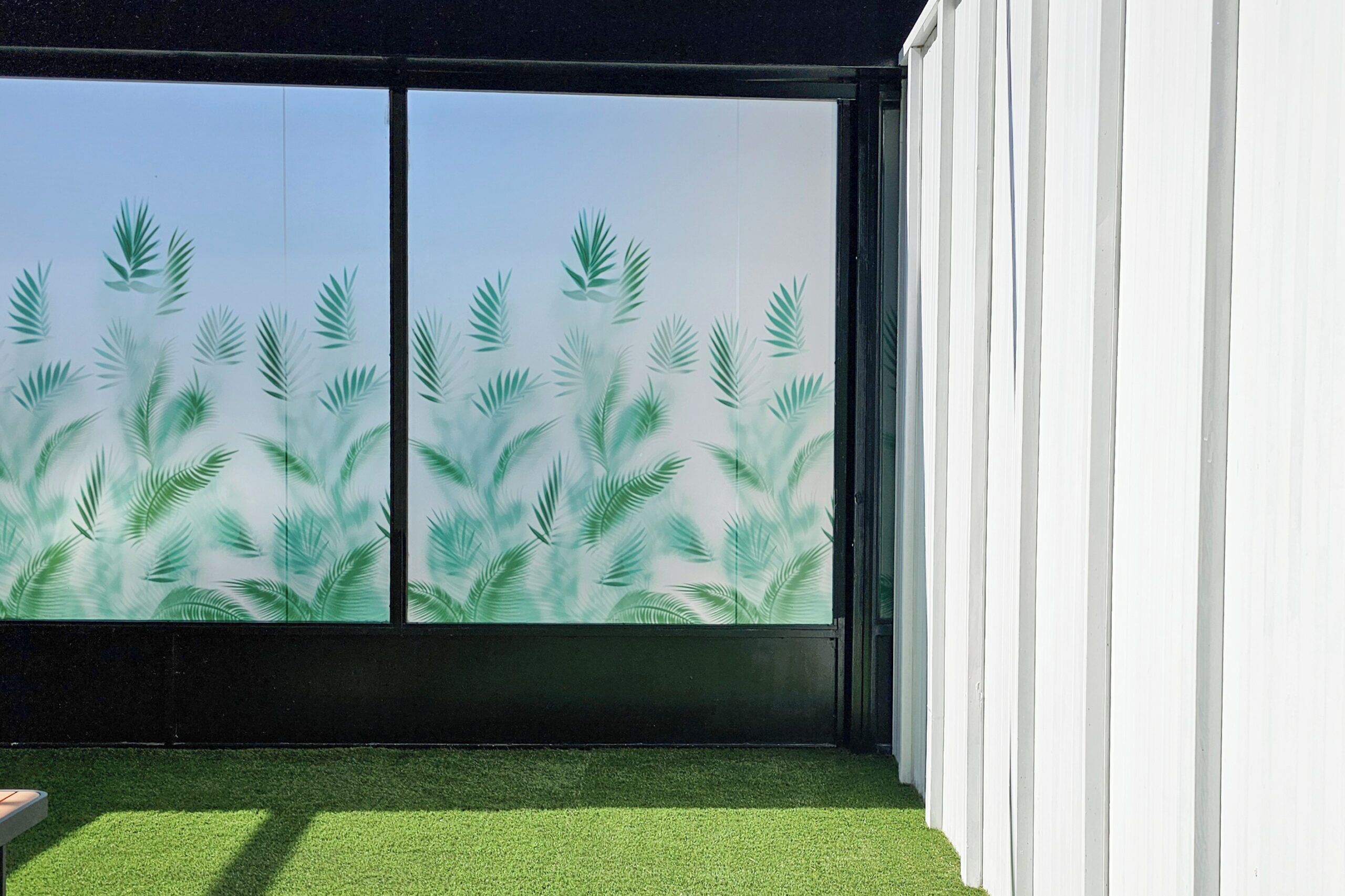 A room with a large sliding glass door featuring a palm leaf pattern.