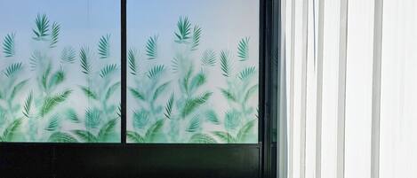 A room with a large sliding glass door featuring a palm leaf pattern.