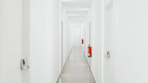 A long, narrow hallway with white walls and doors on either side. - Ros Lil Suites (Alicante)
